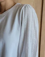 Remera blanca de algodón con mangas 3/4 abullonadas y cuello redondo. Presenta costuras a contratono en ruedo y cuello.