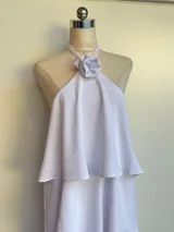 Minivestido negro con escote halter con detalle de flor, corte escalonado y falda corta.