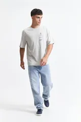 Remera marrón de manga corta con corte oversize y cuello redondo. Estampado en la espalda con diseño abstracto y texto.