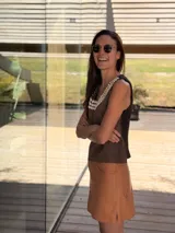 Top negro de cuero con escote en V y apliques de caracoles cosidos a mano en el escote.