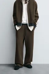 Pantalón jogger color verde oliva, corte relaxed fit, con cintura elástica ajustable con cordón, bolsillos laterales y detalle de bolsillo de vivo en la espalda. Presenta una banda lateral color crema a contraste.