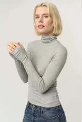 Remera de punto rib fino en color blanco, con cuello alto plegable y mangas largas. Presenta un calce ceñido y puños con abertura para el pulgar.