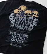 Remera negra de algodón con efecto desteñido (stone wash), corte boxy y manga corta. Estampa grande en la espalda con cinco calaveras amarillas y texto en blanco que dice "SAVAGE SQUAD" y debajo "WE WERE NEVER QUIET".