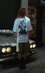 Remera blanca de corte oversize con cuello redondo y manga corta. Presenta un estampado minimalista en el pecho con la frase "Au revoir, shoshanna!" en tipografía negra.