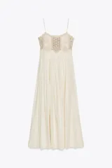Vestido largo color crudo, de algodón, con tirantes finos y escote recto. Presenta detalle de crochet en la parte superior.