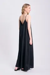 Vestido largo negro con breteles finos y escote en V, de corte amplio y estilo minimalista.