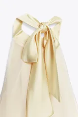 Vestido midi de satén color amarillo pálido, con cuello halter y espalda descubierta.