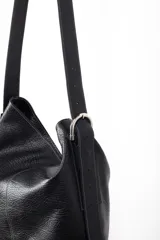 Bolso tipo tote de cuero gamuzado color marrón, con correa de hombro de cuero negro y hebilla metálica. Diseño minimalista y funcional. Confeccionado a mano en Uruguay.