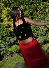 Top negro de corderito natural con breteles y broches en la espalda. Decorado con pins variados.