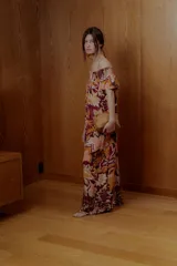 Maxi vestido con estampado floral en tonos naranja, rosa y borgoña. Tiene escote off-shoulder elastizado y mangas cortas con volados.