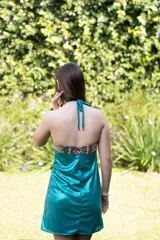 Vestido corto turquesa con escote halter y espalda descubierta. El cuello es alto y las tiras se atan en la nuca.
