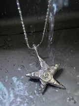 Collar plateado con dije de estrella de cinco puntas con espiral en el centro.