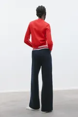 Chaqueta de punto roja con escote pico y manga larga. Tiene vivos laterales combinados a contraste y cierre frontal con botones forrados a tono.
