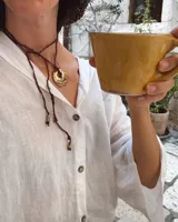 Collar con cordón naranja y dije de flor dorada.