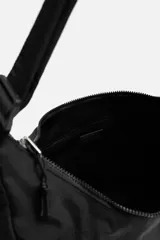 Bolso negro de tela técnica con correa de hombro ajustable. Tiene un compartimento principal con cierre de cremallera, un bolsillo interior con cremallera y tres bolsillos exteriores, uno de ellos con cremallera.