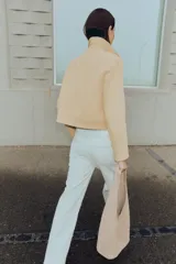 Jeans tobilleros de tiro alto color blanco, corte recto y bajo sin costura. Cierre frontal cruzado con cremallera y botones.