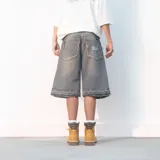 Bermuda de jean gris oscuro con efecto desgastado, corte amplio, largo a la rodilla y ruedo desflecado.