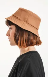 Gorro tipo bucket color marrón con logo de la marca en etiqueta negra.