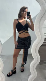 Top negro con textura acanalada y lurex, con tiras finas y corte irregular con tiras cruzadas en el abdomen.