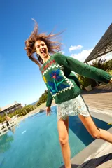 Sweater tejido de lana color verde con bordado de flor y la palabra "Bloom" en el frente. De calce holgado, cuello redondo y puños ajustados.