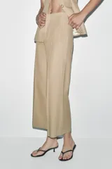 Pantalón culotte gris de tiro alto con bolsillos delanteros de vivo. Pierna ancha y cierre frontal con cremallera y gancho metálico.