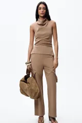 Top color beige de cuello halter y hombros descubiertos, con espalda descubierta, bajo con aberturas laterales y cierre en cuello con botones.