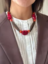 Collar corto con cuentas de resina rojas y naranjas, piedras rojas irregulares y cuentas de madera marrón.