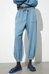 Pantalón jogger celeste confeccionado en lino, con tiro alto, cintura elástica ajustable con cordón, bolsillos delanteros y puños elásticos en el bajo.