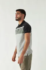Remera tipo polo de manga corta con diseño a bloques de color: negro en cuello y mangas, gris oscuro en la parte superior del pecho, blanco en el centro y gris claro en el resto del cuerpo.