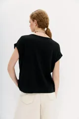 Remera negra de algodón con calce holgado, cuello redondo, largo crop y mangas cortas rebatidas.