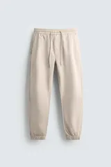 Pantalón jogger negro de corte slim fit, confeccionado en tejido de algodón con cintura elástica ajustable con cordón, bolsillos frontales y traseros de vivo, y bajo con puño elástico.