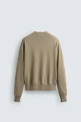 Jersey de hombre color beige, de corte relaxed fit, tejido en hilatura con algodón y ramio. Tiene cuello pico, manga larga y acabados en rib.