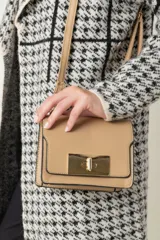 Cartera pequeña de imitación cuero color beige, con broche metálico dorado y asas ajustables.