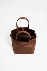 Bolso tote pequeño marca Bimba y Lola, modelo Chihuahua, color marrón. Confeccionado en nylon con estructura blanda, doble asa de mano y asa de tejido, piezas de piel, cierre con botón de presión, logo grabado, acabados metálicos, bolsillo interior e interior con placa metálica logotipada.