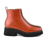 Bota corta color marrón con plataforma y taco bajo. Presenta detalle de costuras en la parte delantera y cierre lateral.