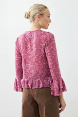 Blusa fucsia estampada con volados, escote en V y mangas largas acampanadas.