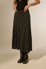 Falda larga de poliéster, color negro con estampado de lunares blancos. Corte amplio y fluido.