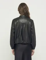 Camperita estilo bomber de eco cuero negra, con cuello mao y cierre frontal metálico. Presenta mangas largas con puños elásticos y elástico en el bajo.