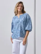 Blusa celeste con estampado floral blanco, escote en V y botones. Mangas 3/4 abullonadas con terminación elastizada.