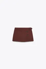 Falda pantalón color marrón óxido de tiro medio, con falsos bolsillos de vivo en la espalda y cierre frontal cruzado con botones y lateral con cremallera oculta en la costura.