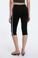 Calzas capri negras con cintura elástica y una raya blanca vertical a lo largo de la pierna.