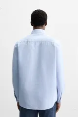 Camisa celeste de algodón, corte relaxed fit, cuello abotonado, manga larga con puños abotonados y cierre frontal con botones.