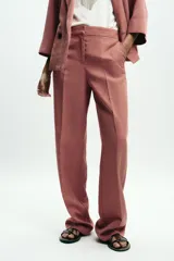 Pantalón de vestir color beige, de tiro alto, con cintura elástica en la parte trasera, bolsillos delanteros y falsos bolsillos de vivo en la parte trasera.