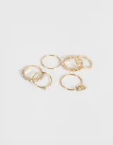 Set de 6 anillos dorados con diferentes diseños, algunos con strass y uno con dije de corazón.