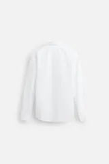 Camisa blanca de corte regular fit, con cuello italiano, manga larga con puños abotonados y cierre frontal con botones.
