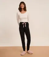 Pantalón de pijama jogger negro con estampado de lunares blancos y lazo rosa en la cintura.