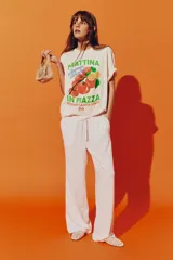 Remera oversized de algodón color crema con estampado de tomates y limones, y texto en italiano en verde y azul.
