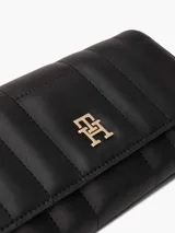 Billetera Tommy Hilfiger negra con diseño acolchado, cierre de solapa y logo metálico TH dorado al frente.