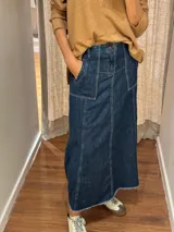Falda midi de jean azul oscuro, con corte evasé, bolsillos frontales y costuras a la vista.