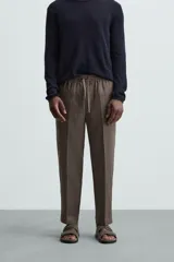 Pantalón negro de lino, corte recto y relaxed fit, con cintura elástica ajustable con cordón, bolsillos laterales y traseros.